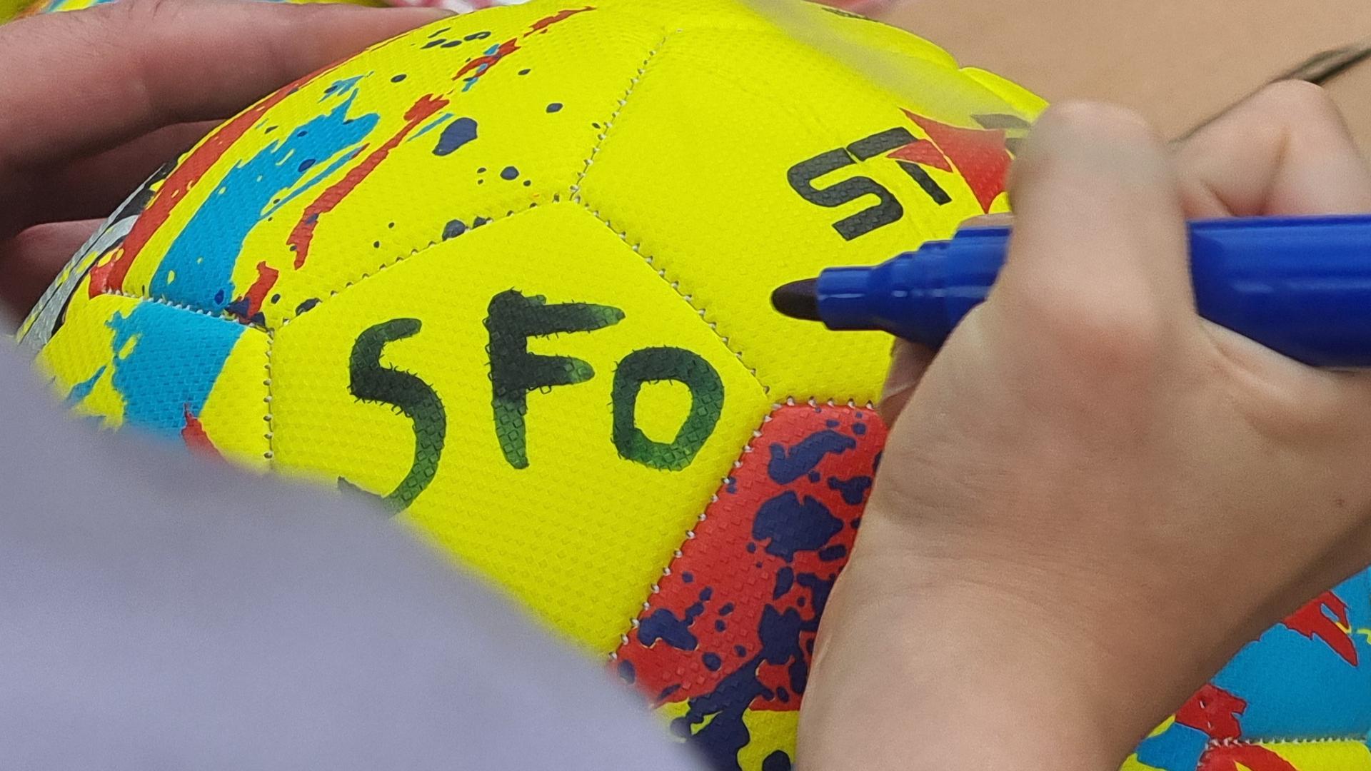 Billede af et barns hænder, der skriver SFO på en fodbold